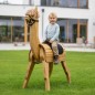 Preview: Kind sitzt glücklich auf einem handgefertigten Holz Alpaka im Garten mit Outdoor-Spielatmosphäre.