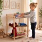 Preview: Mädchen füttert eine Babypuppe am Puppen Wickeltisch aus Holz im hellen skandinavischen Kinderzimmer