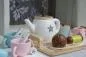 Preview: Ein Teeservice auf dem Tablett mit zwei Teetassen mit eingehängten Teebeuteln und Löffeln, eine Teekanne, Milchkanne und Zuckerdose im Sternendekor stehen auf dem Tisch. Kuchen gehört selbstverständlich auch mit zur Teestunde.