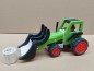 Preview: Grüner Holztraktor mit abgesenktem Greifer neben dem Heuballen