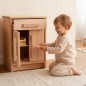Preview: Kind kniet vor Kinder Küchenschrank aus Buche Massivholz und räumt Geschirr ein, fördert Selbstständigkeit und Rollenspiel