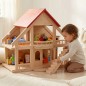 Preview: Kind spielt konzentriert mit großem Puppenhaus aus Holz im hellen Kinderzimmer