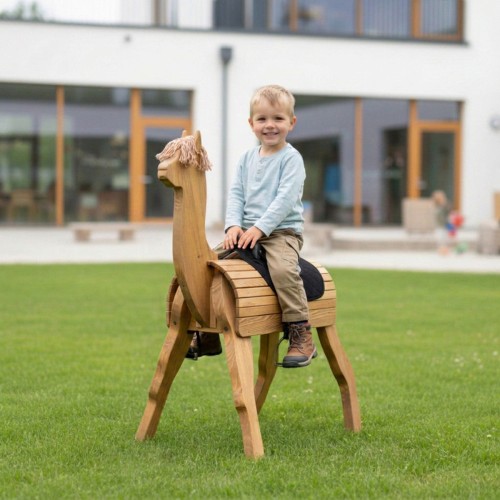 Kind sitzt glücklich auf einem handgefertigten Holz Alpaka im Garten mit Outdoor-Spielatmosphäre.