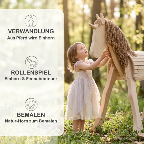 Kind spielt auf Holzpferd mit Einhorn-Horn im Garten – märchenhaftes Rollenspiel mit natürlichem Holzspielzeug