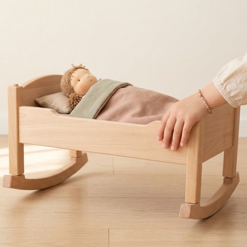 Kind schaukelt liebevoll die Puppenwiege mit schlafender Puppe im Rollenspiel.