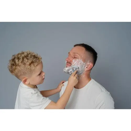 Vater wird von seinem Sohn rasiert und verwöhnt mit einer Bartpflege