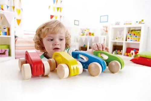 Kind spielt mit kleinen, bunten Holz-Rennautos.