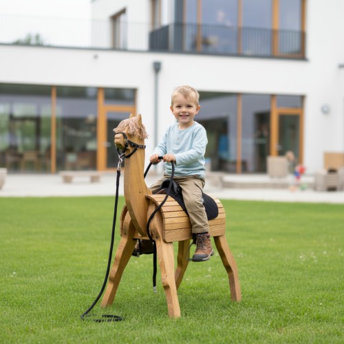 Kind spielt auf großem Holz Alpaka DIEGO im Garten – die pädagogische Spielpferd Alternative fördert die Fantasie.