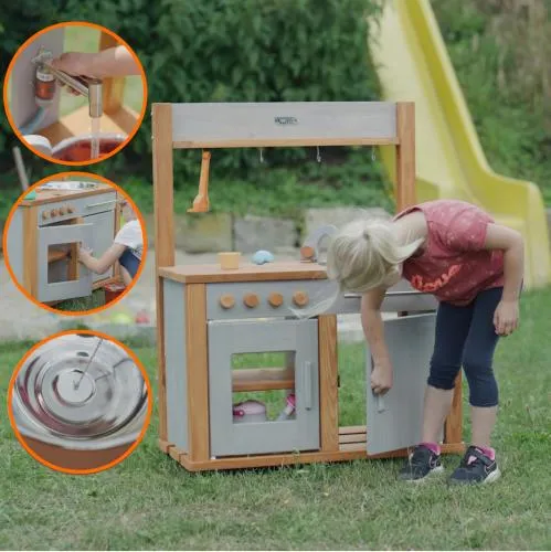 Kind spielt mit schoener Matschkueche draussen im Garten