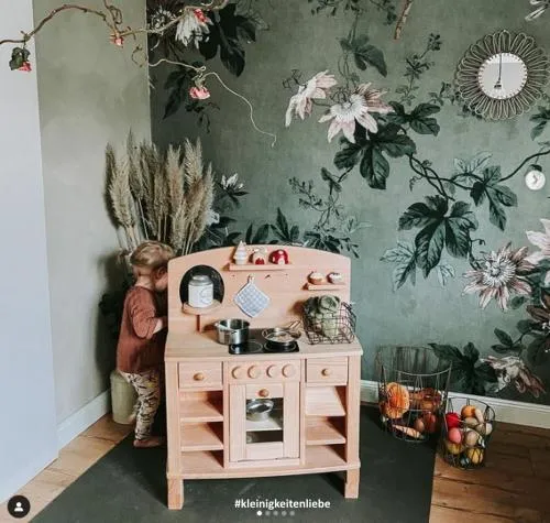 Kind spielt mit Cinderella Küche im Wohnzimmer. Frontansicht mit Gemüsekörben.