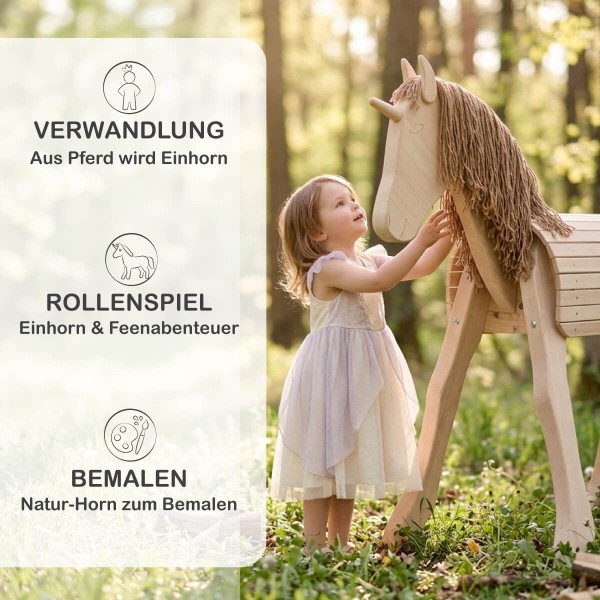 Kind spielt auf Holzpferd mit Einhorn-Horn im Garten – märchenhaftes Rollenspiel mit natürlichem Holzspielzeug