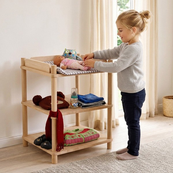 Mädchen füttert eine Babypuppe am Puppen Wickeltisch aus Holz im hellen skandinavischen Kinderzimmer