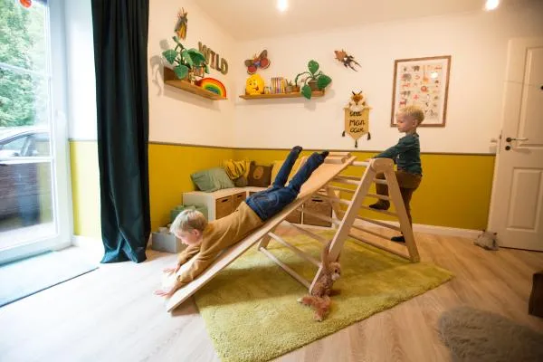 Zwei Kinder spielen mit Kletterdreieck und Rutsche im Kinderzimmer
