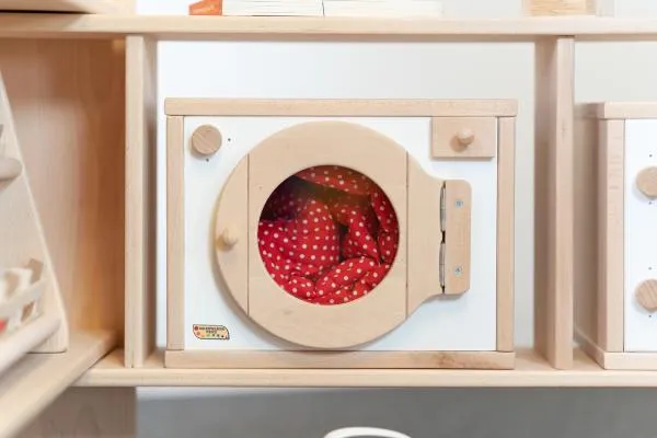 kinder-waschmaschine natur-weiß eingebaut in spielständer mit anderen küchenelementen von holzspielzeug peitz