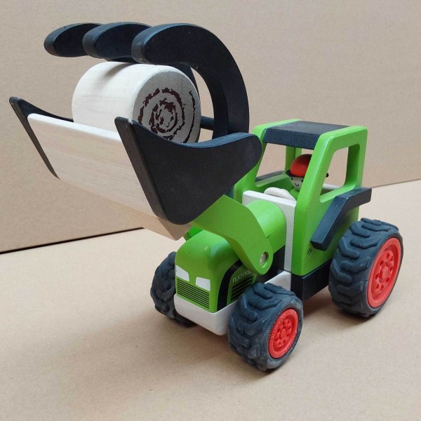 Grüner Holztraktor mit Fahrerfigur und Heuballen im Frontlader