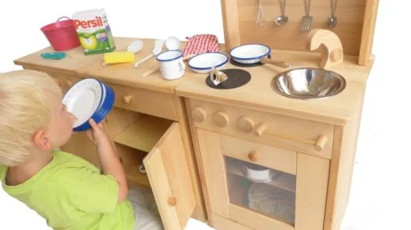 Kind spielt mit Spielküche, räumt das Geschirr ein