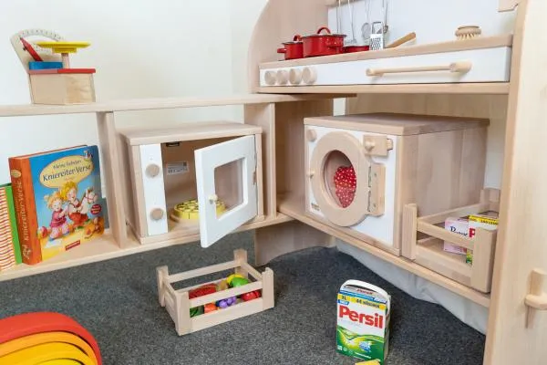 Mikrowelle, Backofen aus Naturholz in Spielständer mit Erweiterung eingebaut. Mit Waschmaschine und Tischküche natur-weiß, Obststiegen, Büchern und Spielzeug