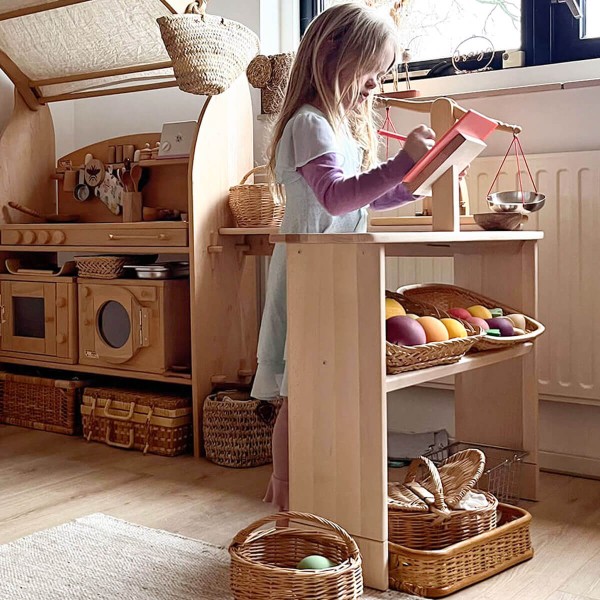 Kind spielt an Holz Spieltheke – kreatives Rollenspiel im Spielhaus